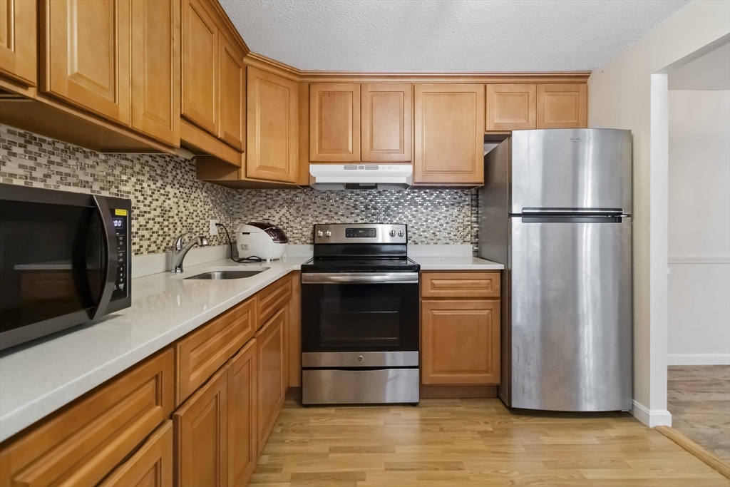 388 Great Road, Unit B14 Acton, MA 01720 - Photo 11 of 24 a kitchen with appliances a refrigerator and cabinets