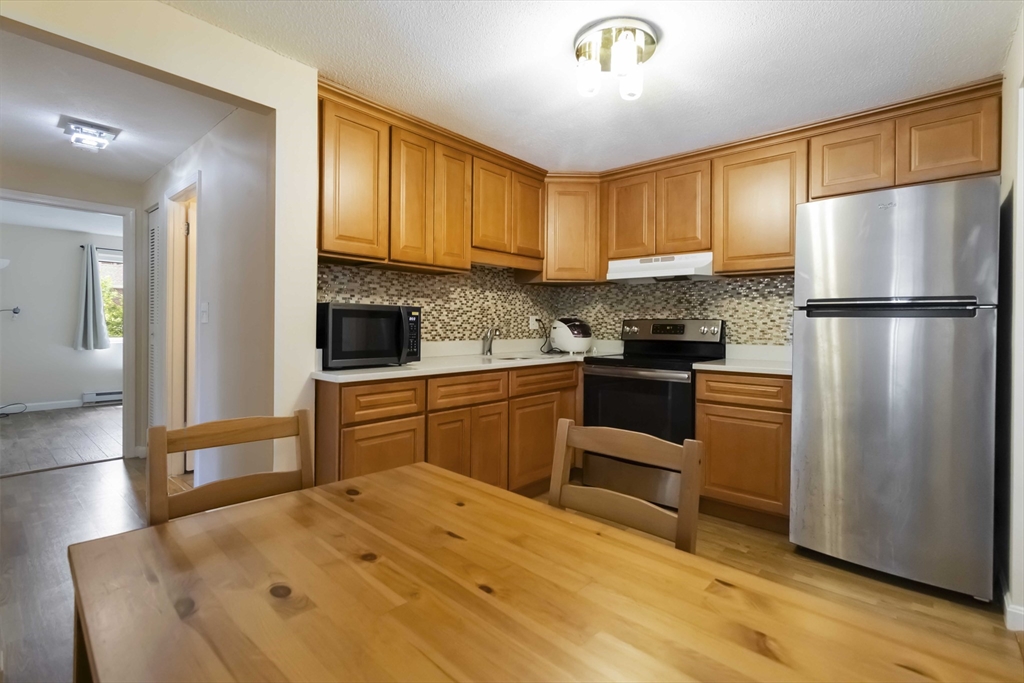 388 Great Road, Unit B14 Acton, MA 01720 - Photo 13 of 24 a kitchen with a refrigerator cabinets and wooden floor