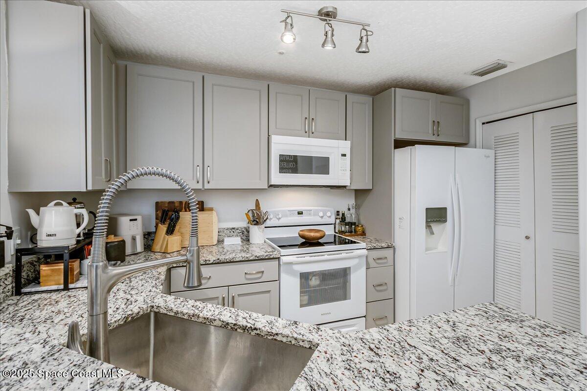 7667 North Wickham Road, Unit 118 Melbourne, FL 32940 - Photo 4 of 23 a kitchen with stainless steel appliances granite countertop a stove top oven a sink a refrigerator and white cabinets