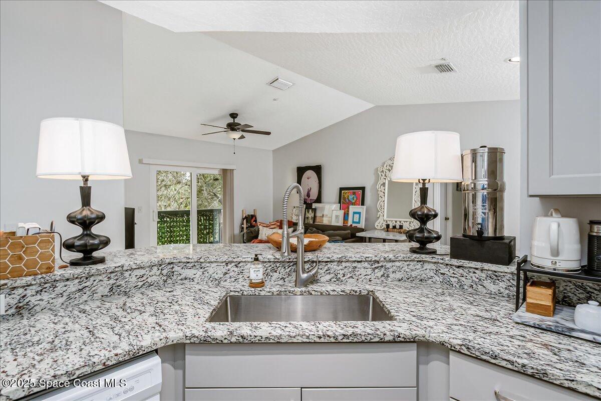 7667 North Wickham Road, Unit 118 Melbourne, FL 32940 - Photo 5 of 23 a kitchen with granite countertop a sink a counter top space cabinets and stainless steel appliances