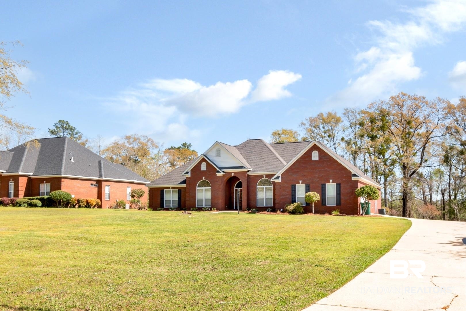 View of front of property featuring driveway, brick siding, and a front lawn