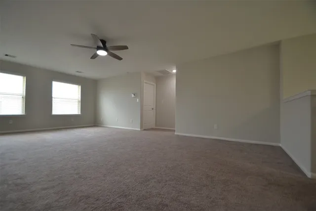 a view of empty room with windows and ceiling fan