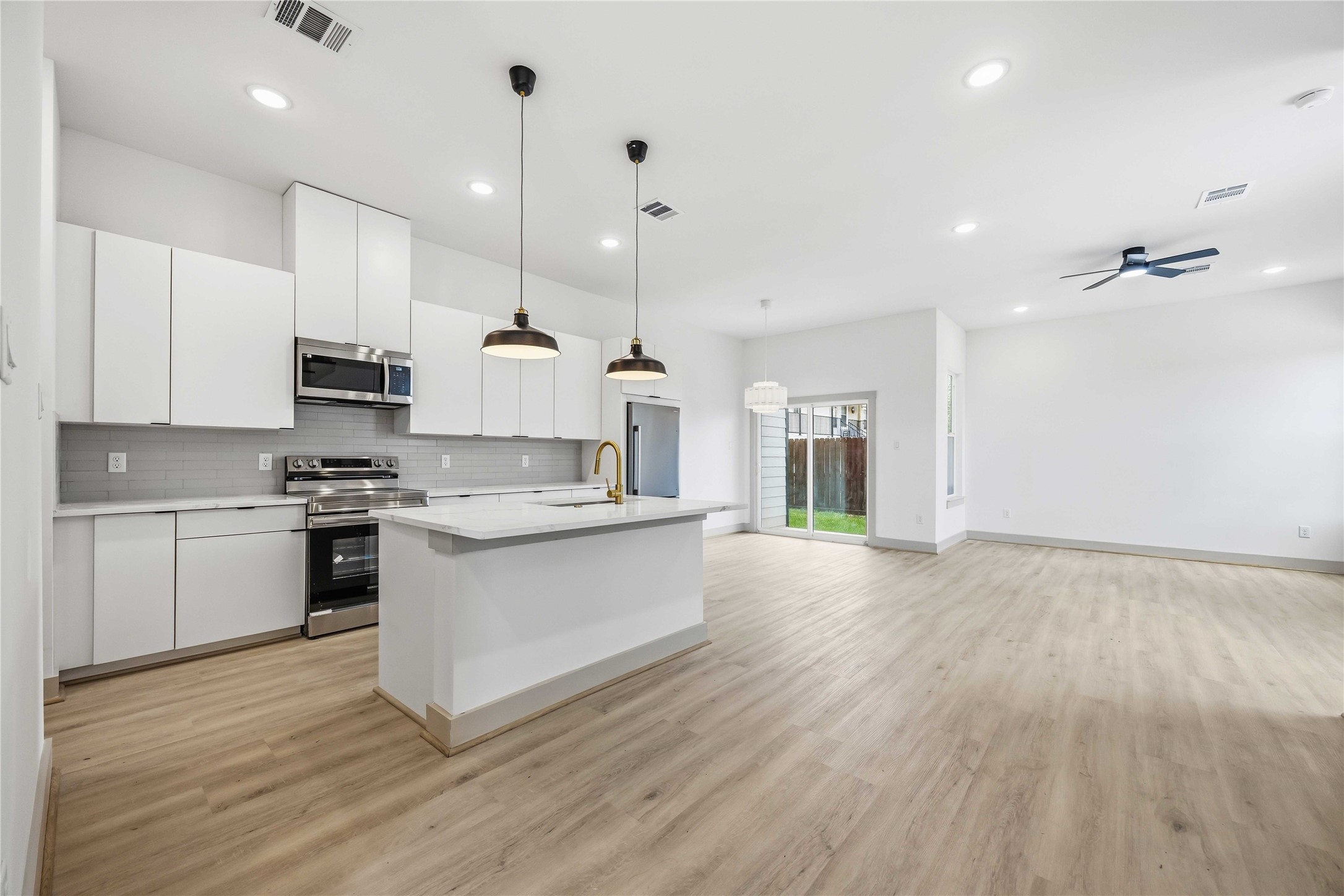 7555 Calhoun Road, Unit A/B Houston, TX 77033 - Photo 5 of 27 a large kitchen with granite countertop a stove a sink a refrigerator and white cabinets with wooden floor