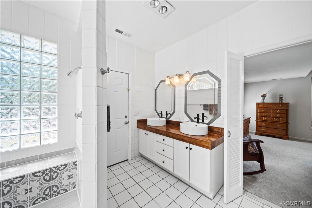 12700 Coalboro Road Chesterfield, VA 23838 - Photo 32 of 50 a en suite bathroom with a double vanity sink a mirror a window and a shower