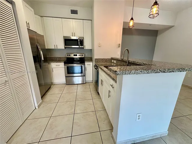 a kitchen with granite countertop a stove top oven and cabinets