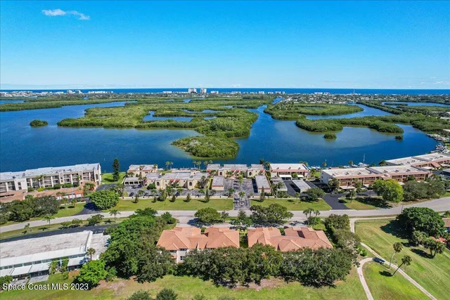 an aerial view of ocean and residential houses with outdoor space