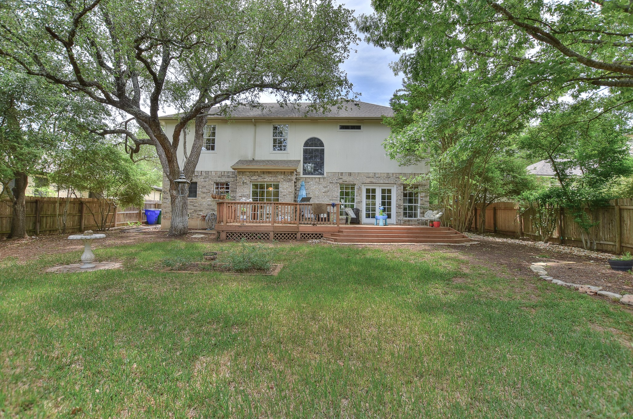 1609 Colton Way Cedar Park, TX 78613 - Photo 17 of 24 A spacious backyard with mature trees frames a multi-level wooden deck and ample green space.
