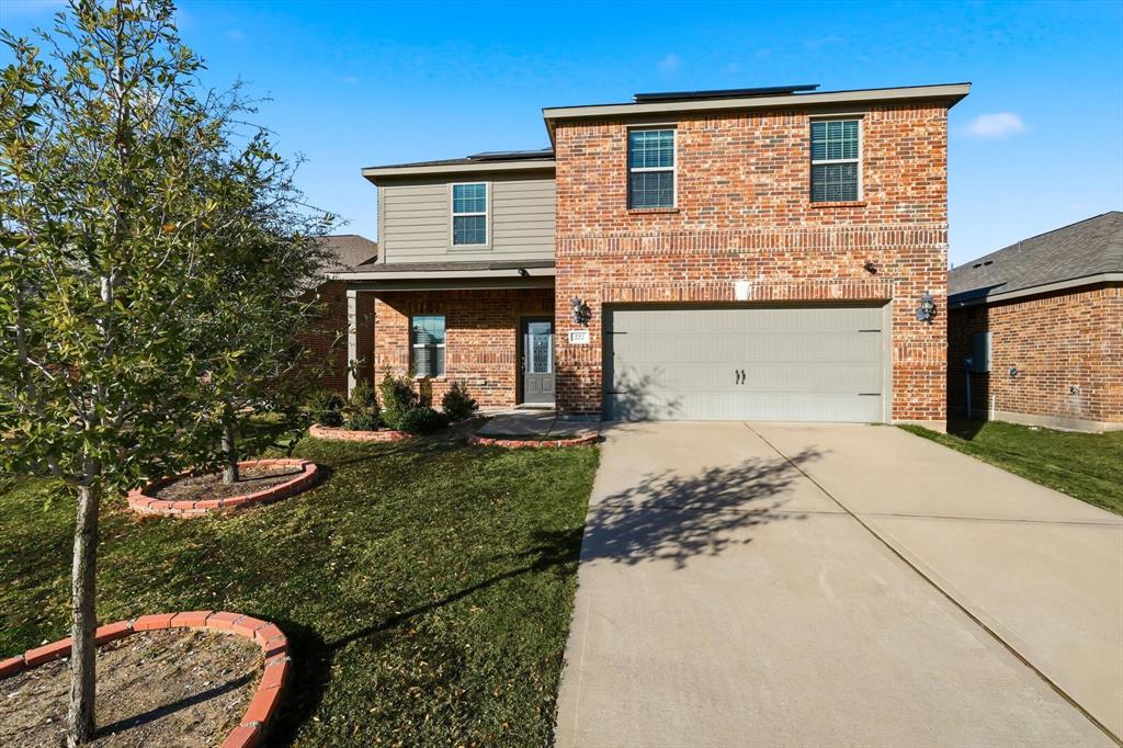 Traditional-style home featuring covered porch, concrete driveway, brick siding, a front yard, and solar panels