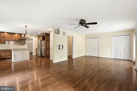 an empty room with wooden floor and a ceiling fan