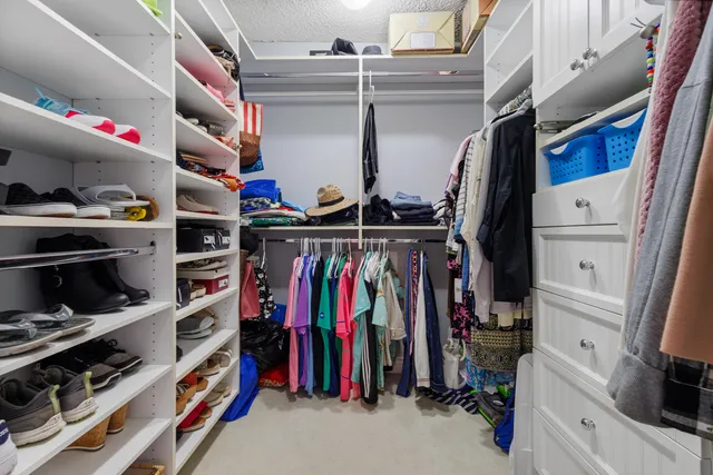 a view of walk in closet with clothes and shoes