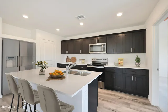 a kitchen with refrigerator a sink and chairs