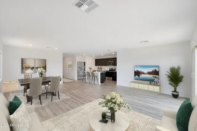 a living room with furniture potted plant and kitchen view