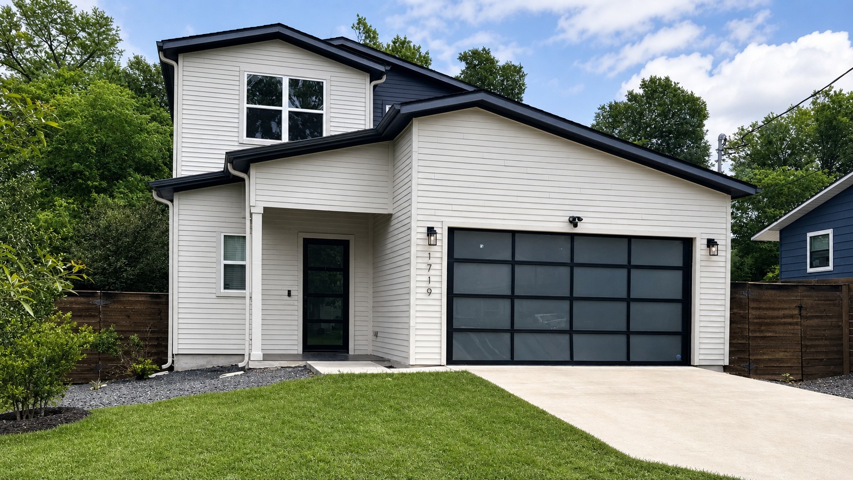 1719 Bunche Road Austin, TX 78721 - Photo 2 of 22 A modern facade with white siding and dark accents welcomes you home, boasting a sleek garage door and concrete driveway.