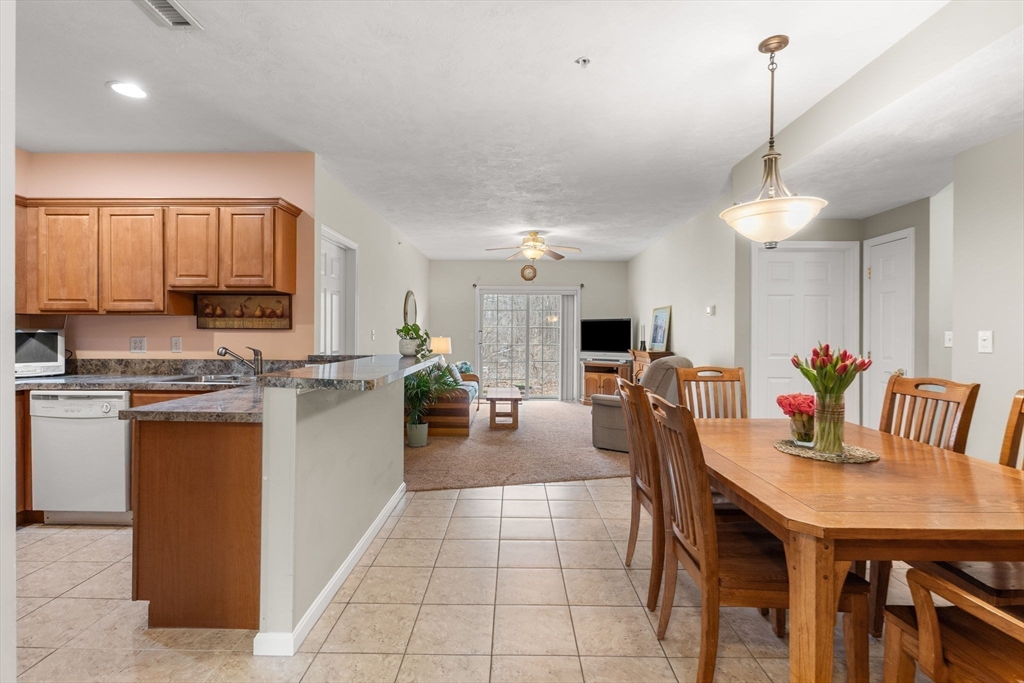 237 Salem Street, Unit 2 Reading, MA 01867 - Photo 5 of 34 a kitchen with stainless steel appliances kitchen island granite countertop a table chairs and a refrigerator