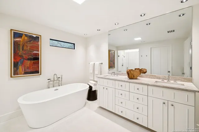 a bathroom with a double vanity sink a mirror a bathtub and