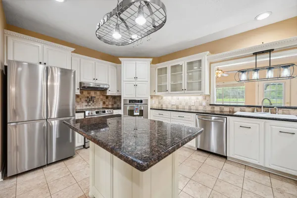 a kitchen with stainless steel appliances granite countertop a sink refrigerator and microwave