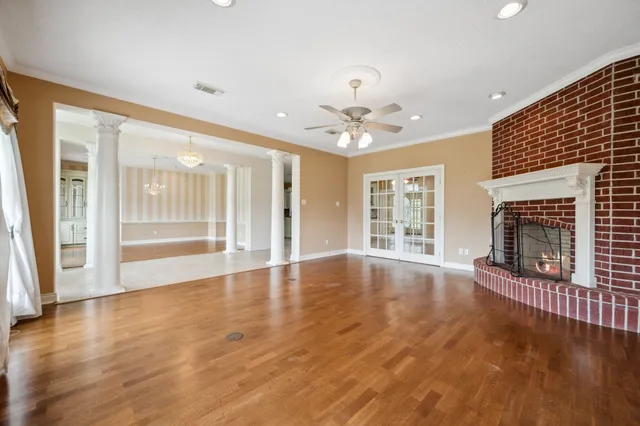 a view of an empty room with wooden floor and a fireplace