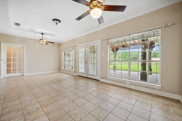 a view of an empty room with a window and chandelier fan