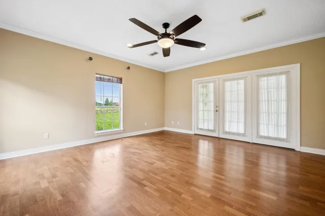 a view of an empty room with a window and wooden floor