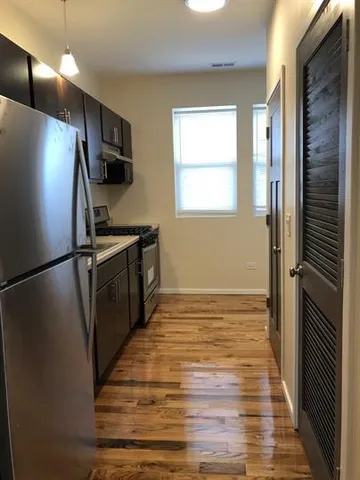 a kitchen with stainless steel appliances a refrigerator and a wooden floor