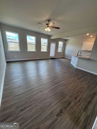 a view of an empty room with window and wooden floor