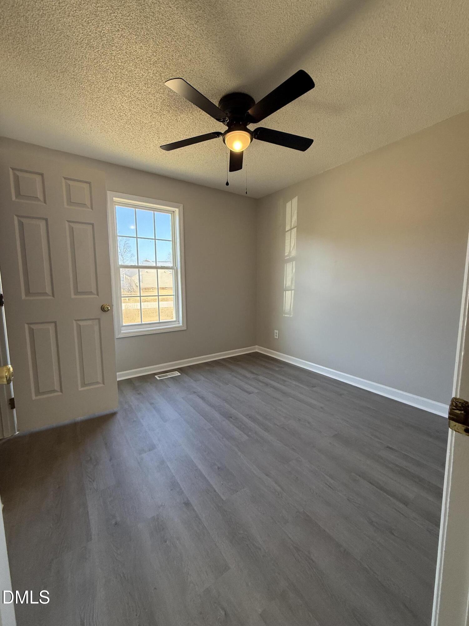 101 Copper Stone Street Smithfield, NC 27577 - Photo 30 of 32 an empty room with wooden floor ceiling fan and windows