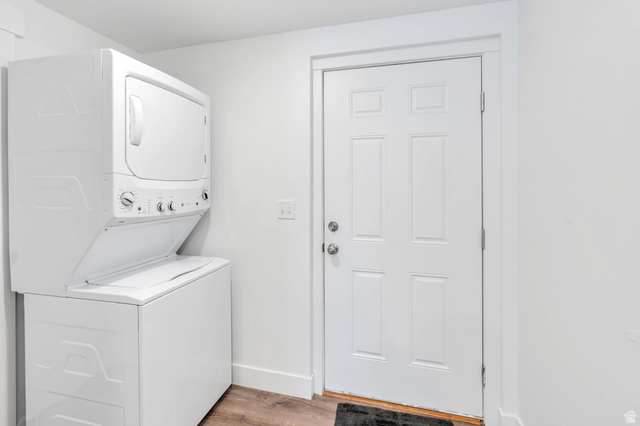 252 North Sunrise Rnch Drive Mapleton, UT 84664 - Photo 41 of 62 Laundry area featuring a white stackable washer and dryer, wood-finish flooring, and a white six-panel door with silver hardware