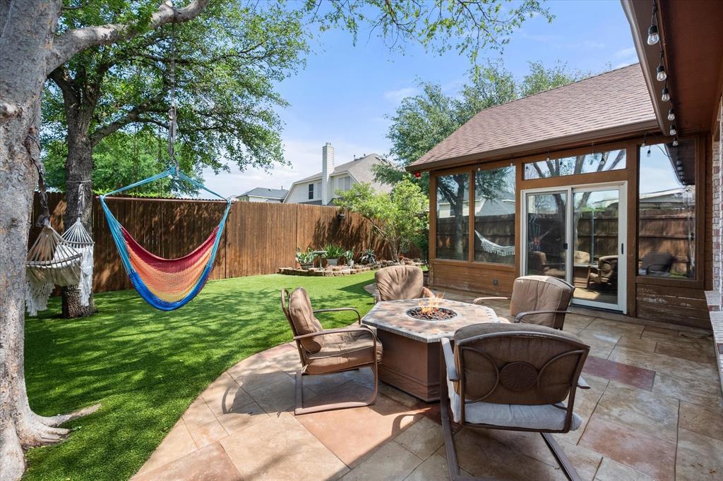 1305 Liverpool Lane Mansfield, TX 76063 - Photo 38 of 40 The property features an outdoor patio area with a fire pit and seating, overlooking a manicured lawn