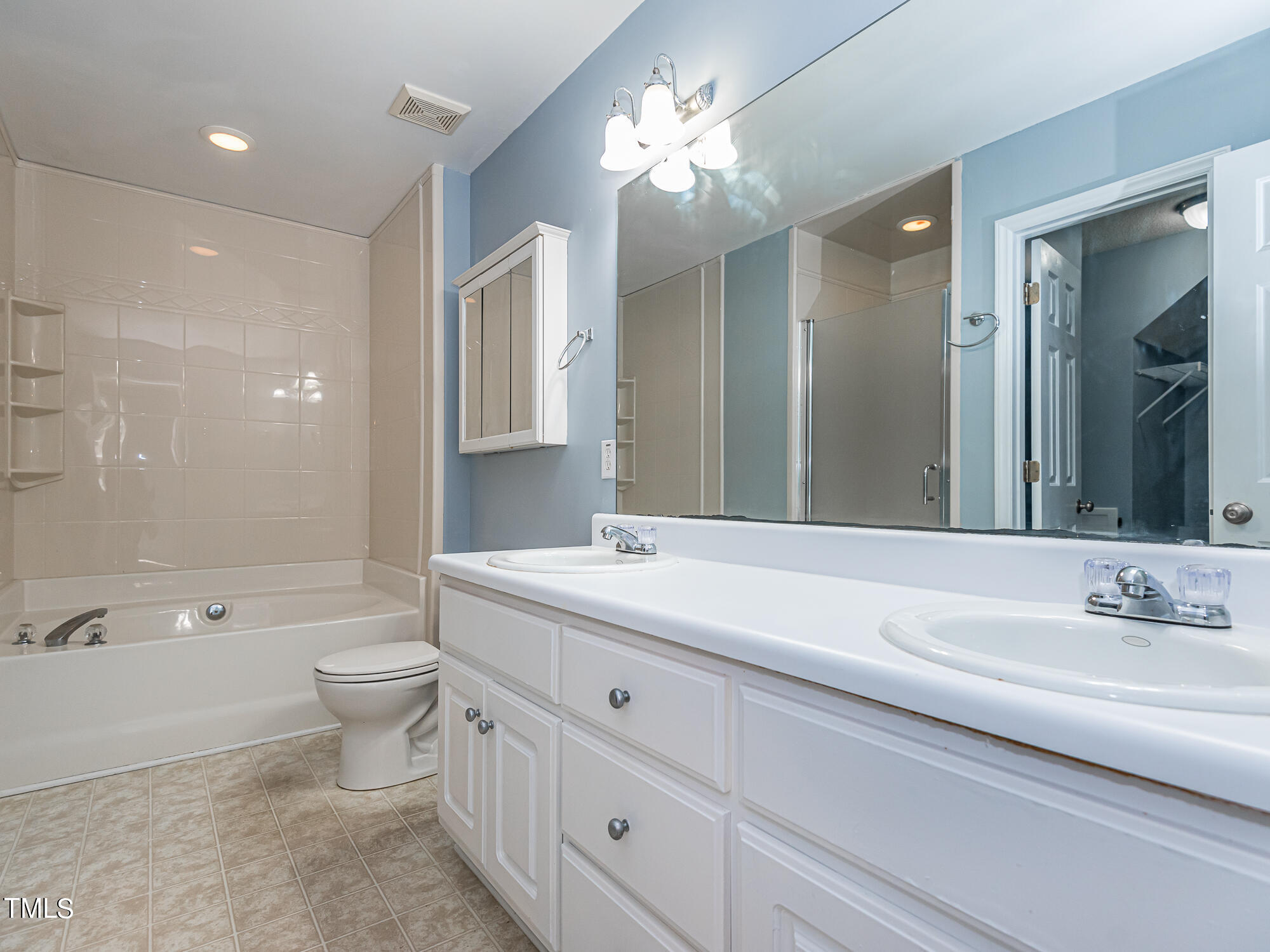 33 Troy Drive Clayton, NC 27520 - Photo 13 of 37 a bathroom with a double vanity sink toilet a large mirror a bathtub and shower
