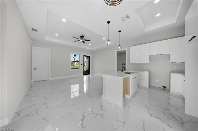 a large white kitchen with window and stainless steel appliances