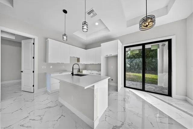 a kitchen with white cabinets and sink