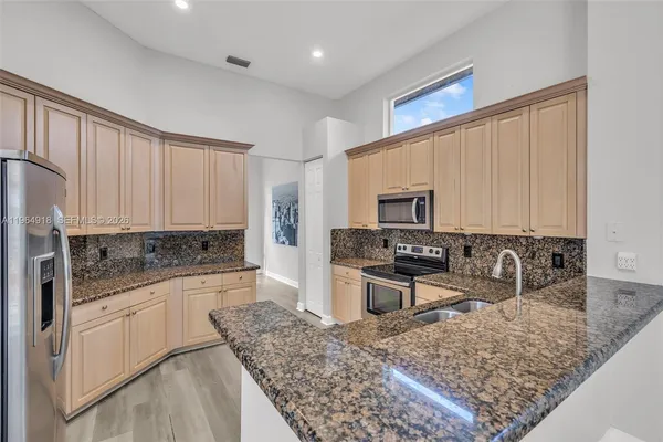 a kitchen with stainless steel appliances granite countertop a sink stove and refrigerator