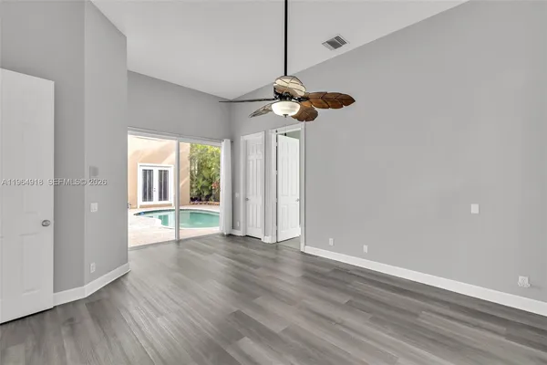 a view of an empty room with wooden floor and a window