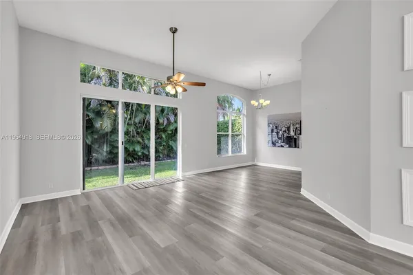 a view of an empty room with window and wooden floor
