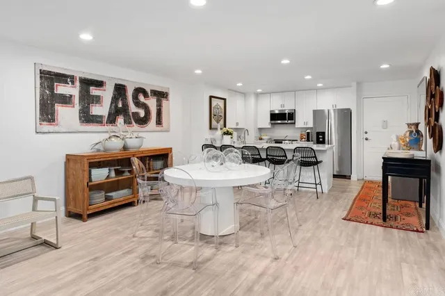 a kitchen with stainless steel appliances granite countertop a dining table chairs refrigerator and microwave