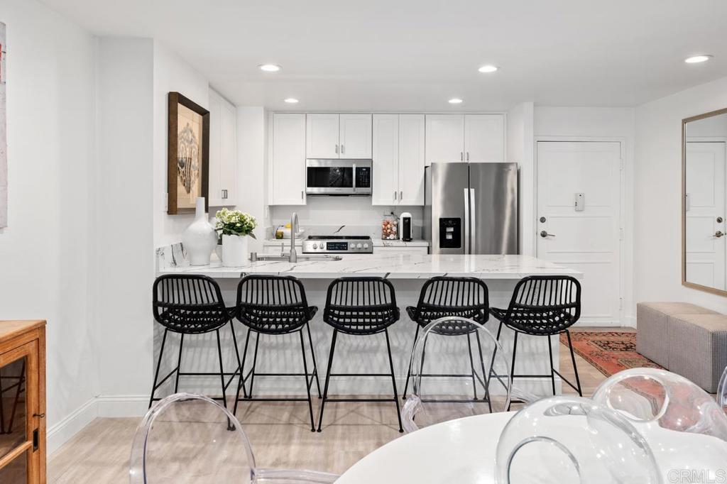 2500 Torrey Pines Road, Unit 201 La Jolla, CA 92037 - Photo 9 of 42 a kitchen with stainless steel appliances kitchen island granite countertop a refrigerator a stove a sink and white cabinets