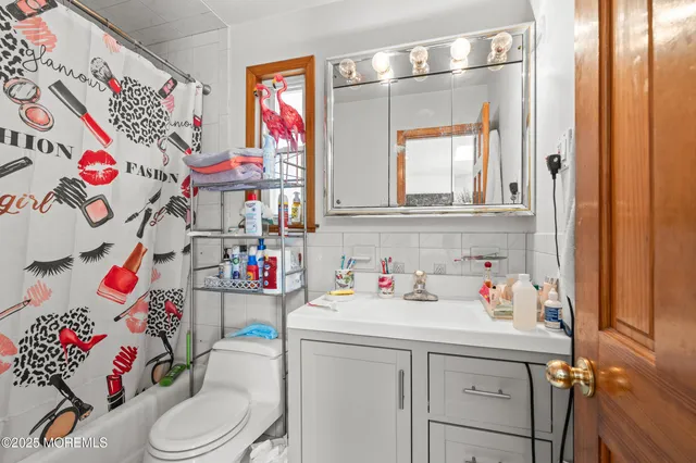 a bathroom with a sink toilet vanity and curtain