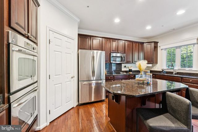 a kitchen with a refrigerator a stove a sink dishwasher with a dining table and chairs with wooden floor