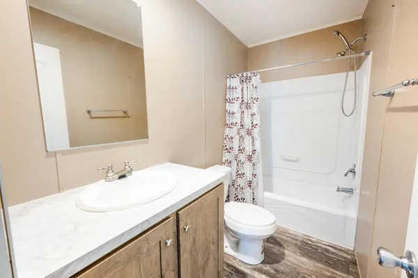 a bathroom with a granite countertop sink toilet a shower and a mirror