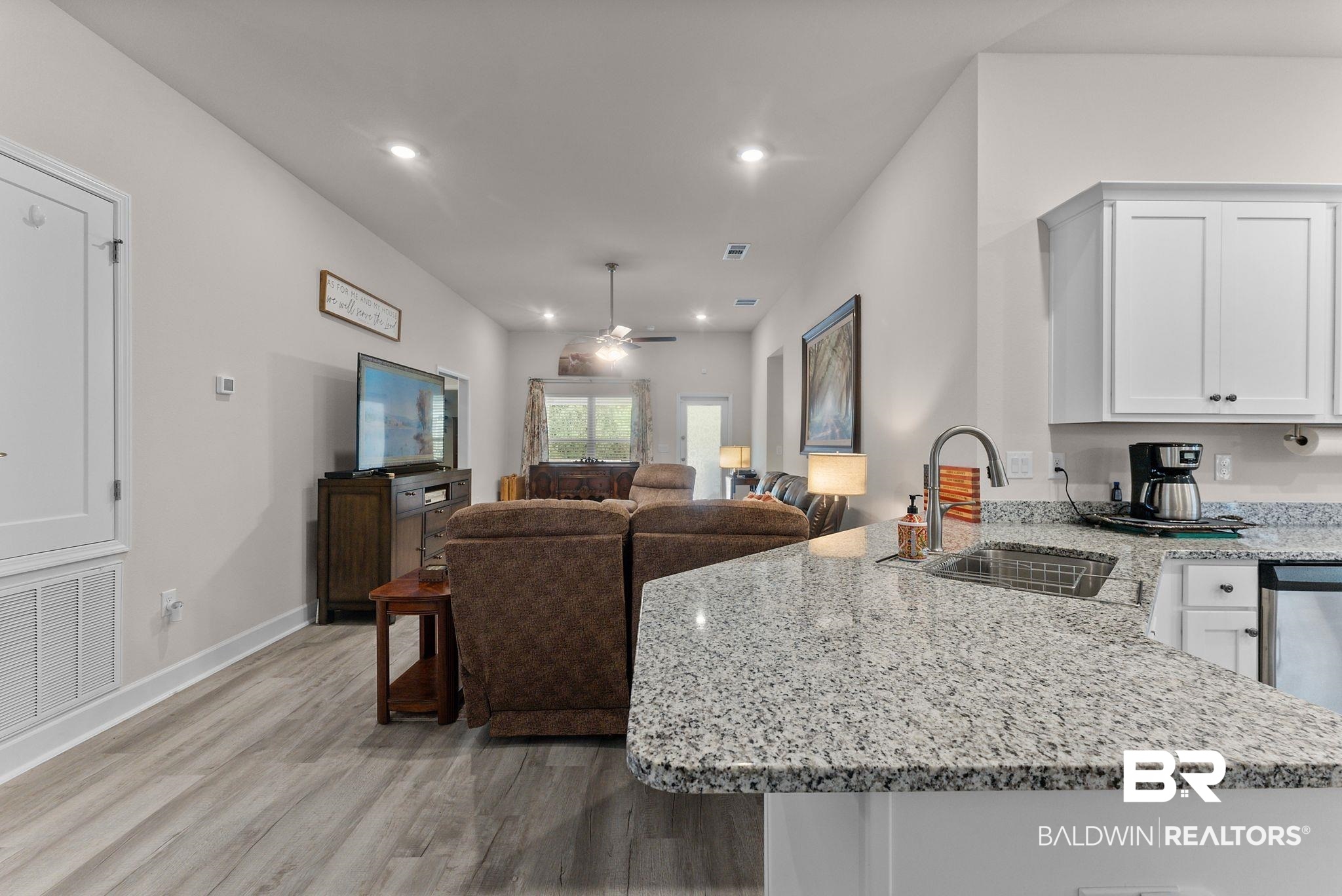692 Mayflower Drive Foley, AL 36535 - Photo 40 of 40 Kitchen featuring light stone counters, a peninsula, ceiling fan, open floor plan, and light wood-style flooring