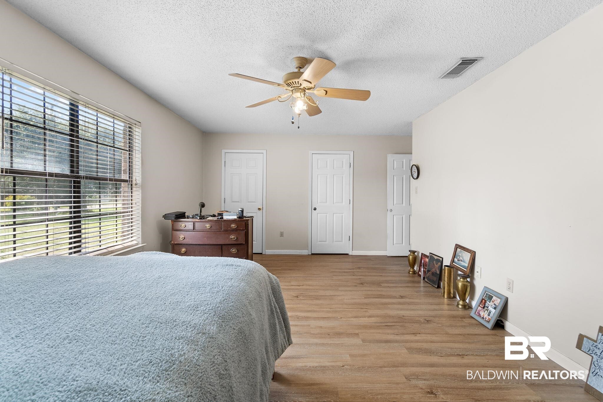 33135 Collier Road Lillian, AL 36549 - Photo 17 of 30 Bedroom featuring light wood-style floors, a textured ceiling, ceiling fan, and two closets