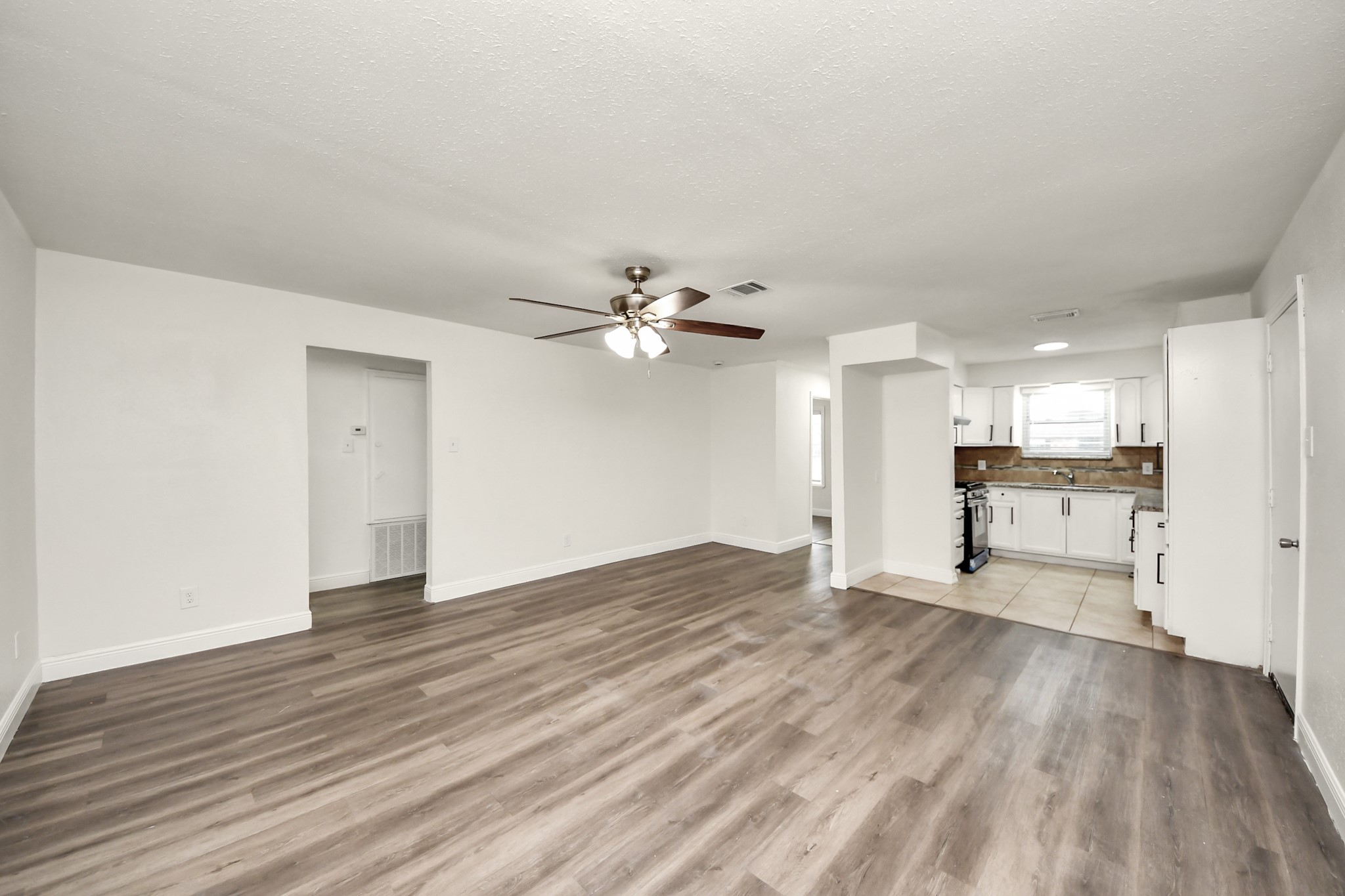 1139 Hartwick Road Houston, TX 77037 - Photo 18 of 38 a view of an empty room with wooden floor and a kitchen