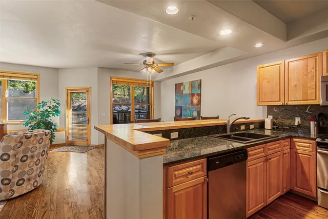 a view of a kitchen with kitchen island a large window cabinets a sink and stainless steel appliances