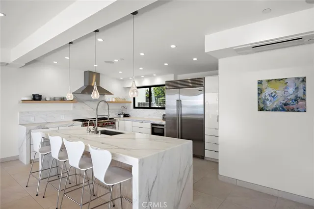 a kitchen with stainless steel appliances kitchen island granite countertop a refrigerator a sink a stove a dining table and chairs