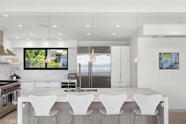 a kitchen with stainless steel appliances kitchen island granite countertop a table chairs and a refrigerator