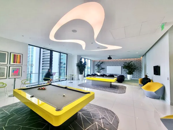 a living room with furniture pool table and kitchen view