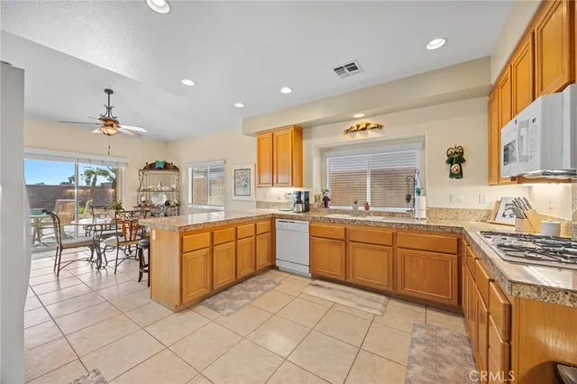 a large kitchen with kitchen island granite countertop lots of white cabinets a sink and appliances