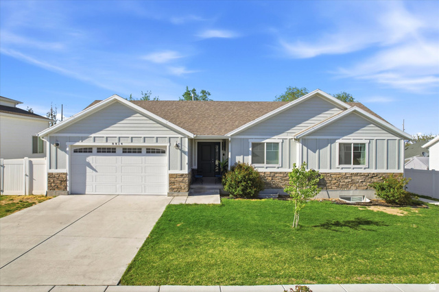 8814 Daisy View Lane Magna, UT 84044 - Photo 1 of 1 View of front of home with stone siding, an attached garage, driveway, and a shingled roof