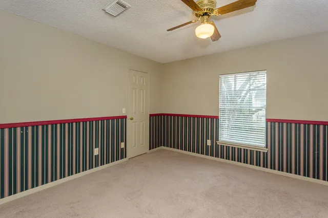 a view of a room with a ceiling fan and carpet