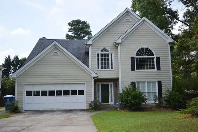 a view of a house with a yard plants and large tree